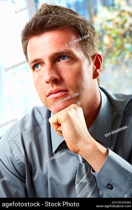 Portrait of confident businessman focusing looking up leaning chin on fist in closeup