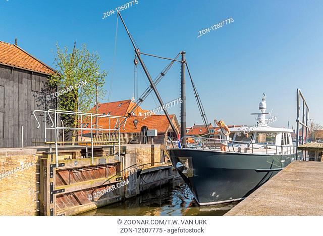 Workum, The Netherlands - April 20, 2018: Modern yacht with woman passing sluice in historic fishing village Workum