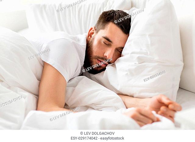 rest, bedtime and people concept- close up of man sleeping in bed at home