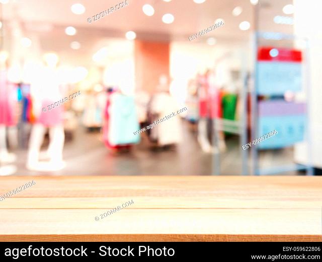 Wooden board empty table in front of blurred background. Perspective light wood table over blur in dress store. Mock up for display or montage your product