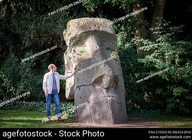 PRODUCTION - 14 September 2021, Hessen, Frankfurt/Main: Jens Söring stands next to a giant replica of a Moai sculpture in Frankfurt's Palmengarten