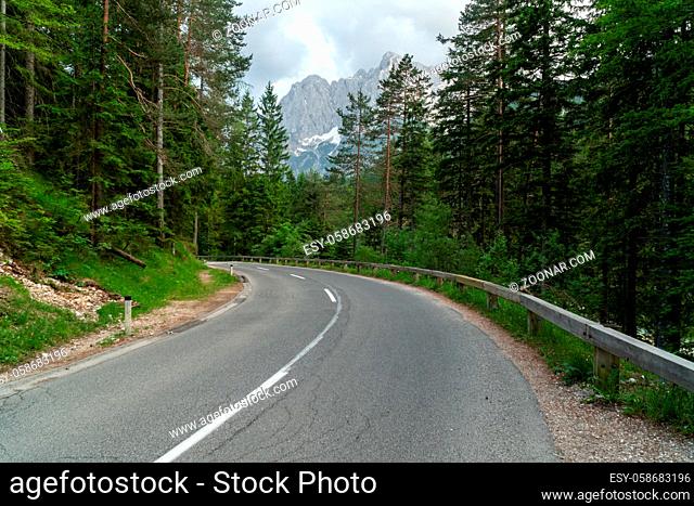 Wide angle photo of beautiful road for cars in the woods with mountains in the back
