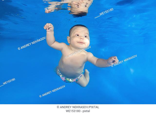 little child learns to swim underwater in the pool