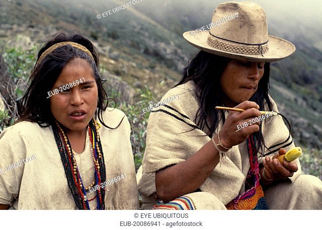 Ika shepherd sitting beside his sister in the high Sierra.He applies powdered lime from a small poporo gourd to a wooden palo stick which he then inserts into a...