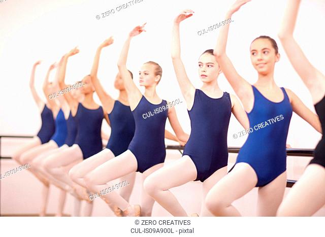 Row of teenage ballerinas with arms outstretched