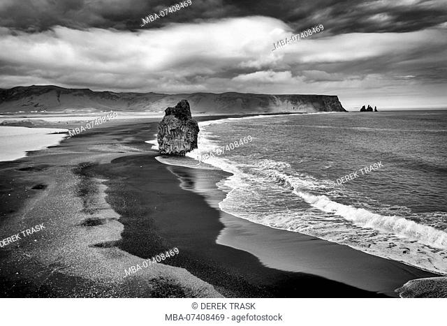 The Black Beach near Vik, Iceland, Arnardrangur or 'Eagle Rock', eagles nested there until 1850, Reynisfjara black sand beach created by lava flowing into the...