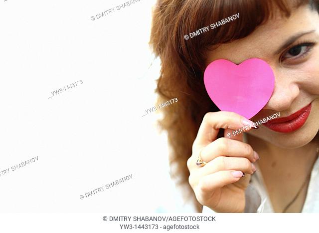 Pretty redhead young woman portrait with heart indoors