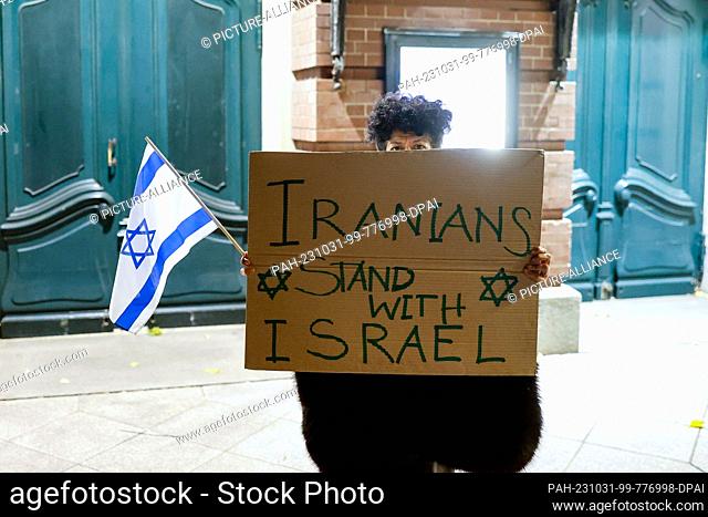 31 October 2023, Hamburg: An Iranian woman stands in front of the Laeiszhalle with a poster reading ""Iranians stand with Israel"" at the solidarity concert for...