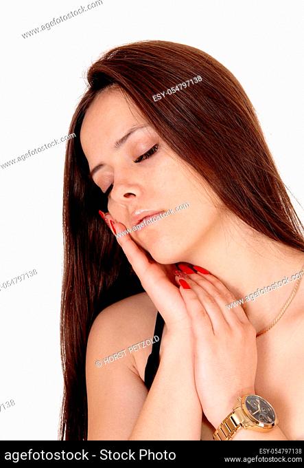 A lovely young woman standing in a black outfit with both hands on.her face, closed eyes, sleeping, isolated for white background