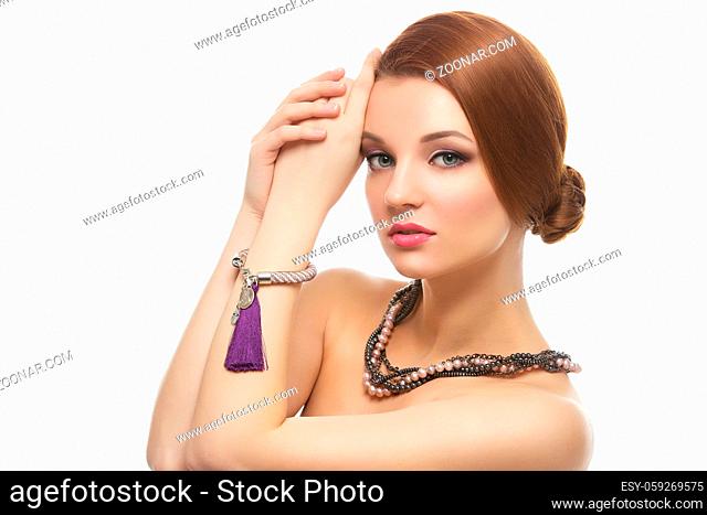 Portrait of beautiful young woman with red hair in natural stones necklace and bracelets. Isolated over white background. Copy space