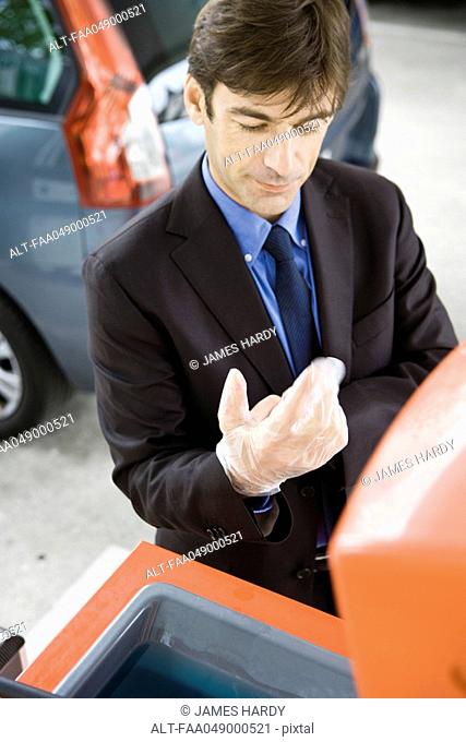 Man taking off disposable gloves after refueling vehicle