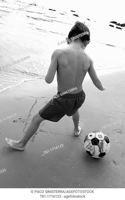 Boy playing soccer on the beach