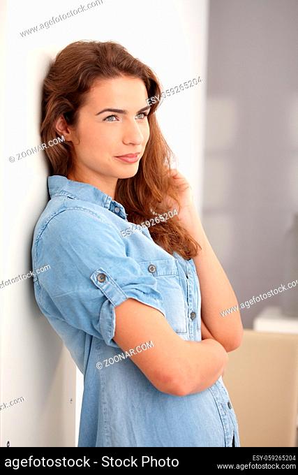 Young attractive woman standing at wall, smiling, looking away