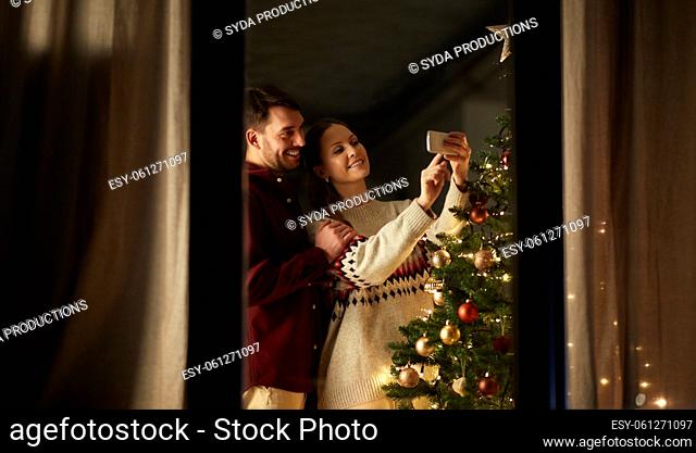 couple taking selfie at christmas tree at home