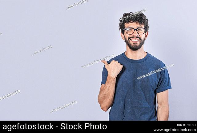 Cheerful bearded man with a friendly smile shows you the direction to a nice place, a friendly guy pointing his thumb to his right