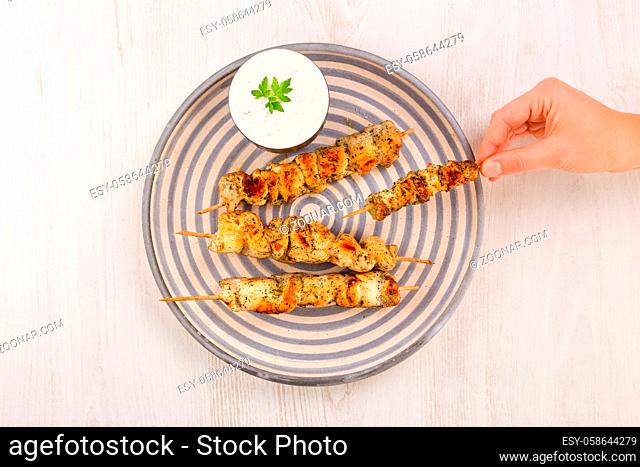 Chicken satay in female hand on plate, top view . BBQ food concept