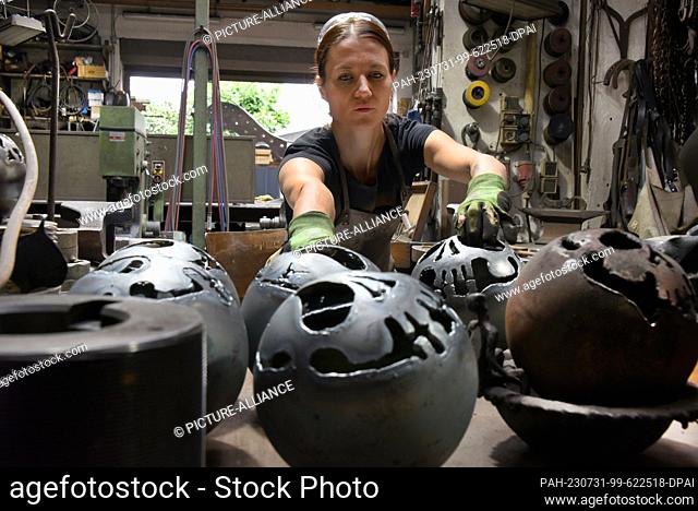 27 July 2023, Saxony, Hohenprießnitz: The 39-year-old blacksmith and metal designer Marika Widdermann works in the forge of her father Roger Widdermann on...
