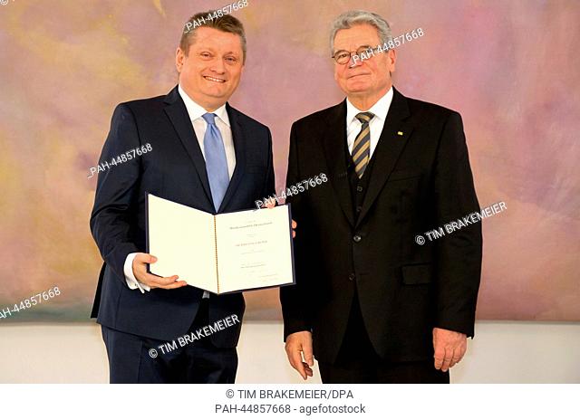 German President Joachim Gauck (R) gives the appointment document to the new German Health Minister Hermann Groehe (CDU) in Bellevue Palace in Berlin, Germany