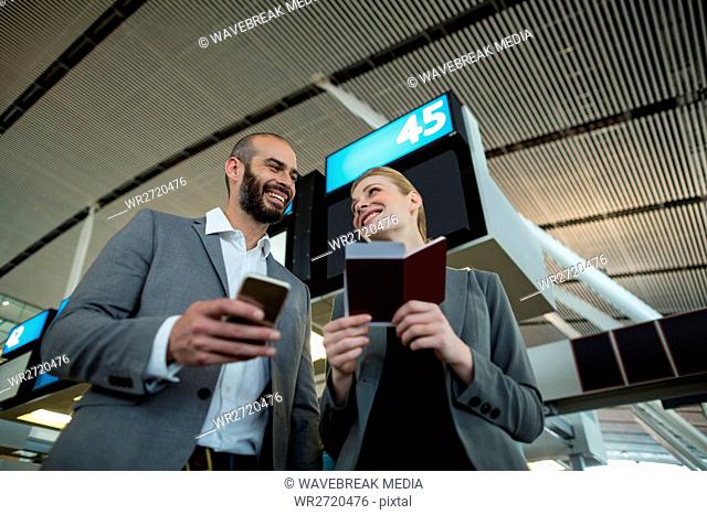 Business people holding boarding pass and using mobile phone