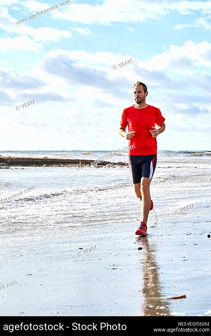 Man running at beach on sunny day