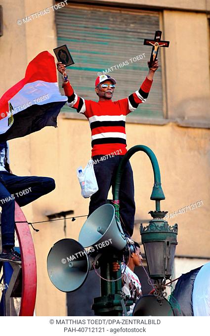 A man holds a cross and a Quran at a demonstration against Egyptian President Mursi at Tahrir Square in Cairo, Egypt, 29 June 2013