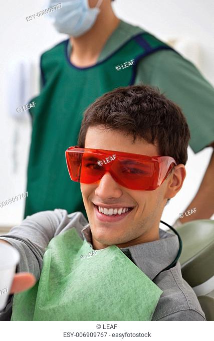 Portrait of patient at dental clinic with dentist standing in background