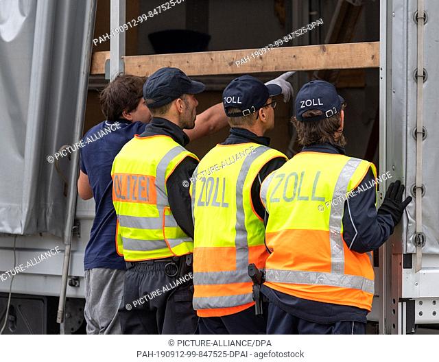 12 September 2019, Saxony, Wilsdruff: A policeman and customs officers check the cargo of a transporter from Poland at the rest stop Dresdner Tor on the A4