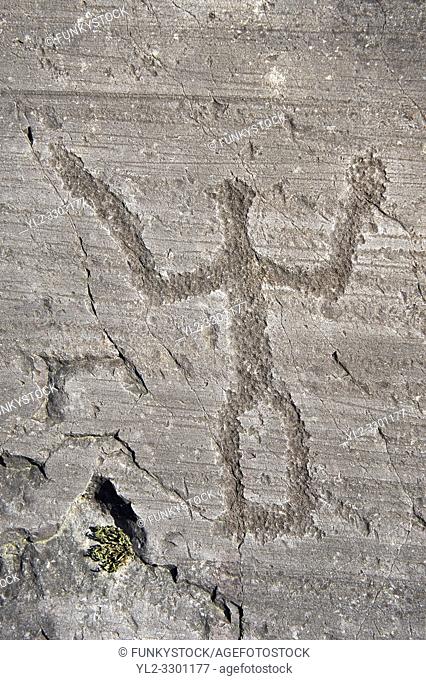 Petroglyph, rock carving, of a schematic warrior holding a shield and a sword. Carved by the ancient Camuni people in the iron age between 1000-1600 BC