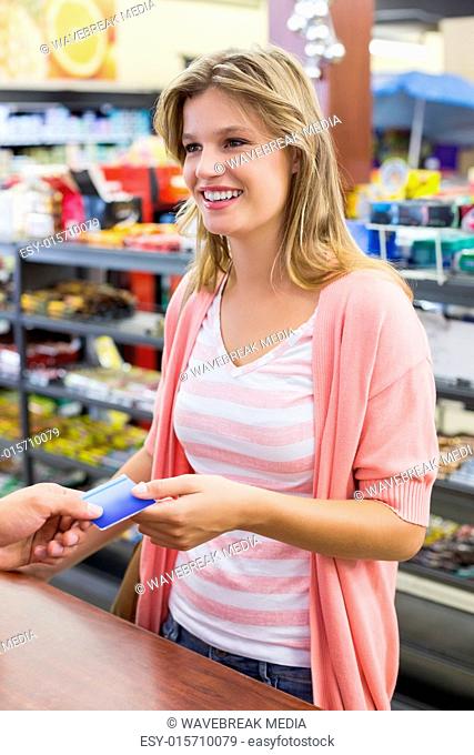 Side view of a smiling woman at cash register paying with credit card