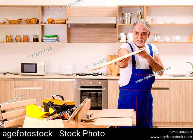 Aged contractor repairman working in the kitchen