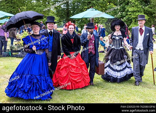 20 May 2023, Brandenburg, Cottbus: People elaborately dressed in clothes of American immigrants from the end of the 19th century walk through the historic...