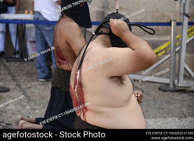 TAXCO, MEXICO - APR 15, 2022: A ‘E’ncruzado’ penitent wears a black hood known as a capirotte, while he flagellates himself