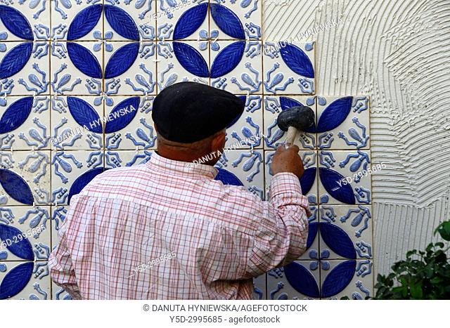 A builder, tiler placing azulejos on adhesive cement, exterior wall, Algarve, Portugal, Europe