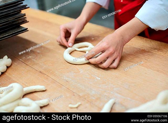 Baker forming pretzels from dough, closeup shot