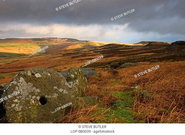 England, Derbyshire, Littlemoor, An old millstone on the Hathersage moorland of the Littlemoor estate.The view takes in Higger Tor in the background