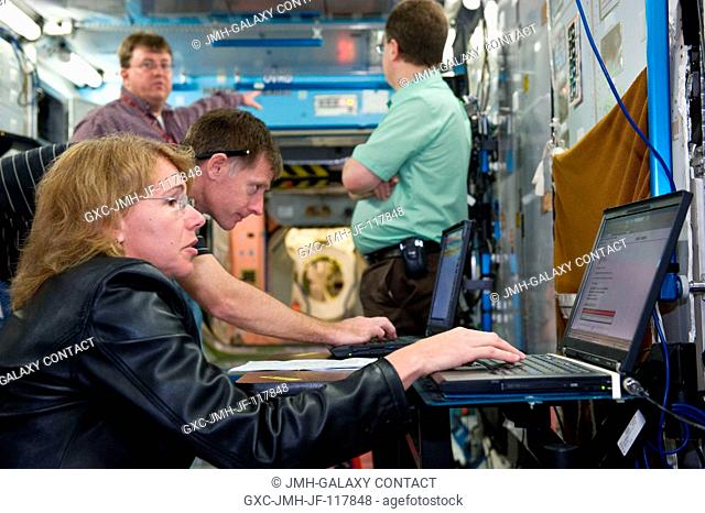 NASA astronaut Chris Ferguson, STS-135 commander; and Sandy Magnus, mission specialist, use computers during a training session in a space station mock-up in...