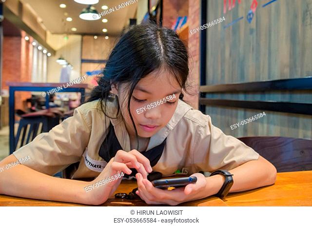 Asian kids playing mobile phone at the dining table