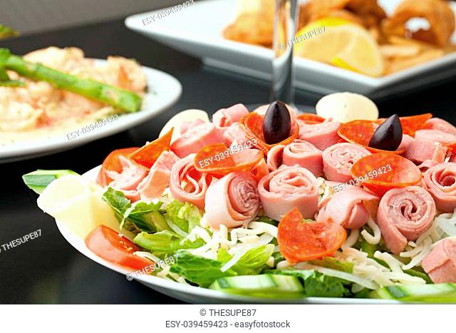 A delicious looking tossed chefs salad or antipasto with meat cheese and kalamata olives