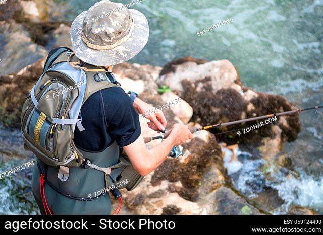 Man fishing in the river. fisher in water. fisherman show fishing technique use. Rod. hobby and sport activity