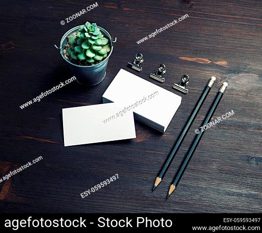 Blank business cards, pencils and plant on wood table background. Branding mock up