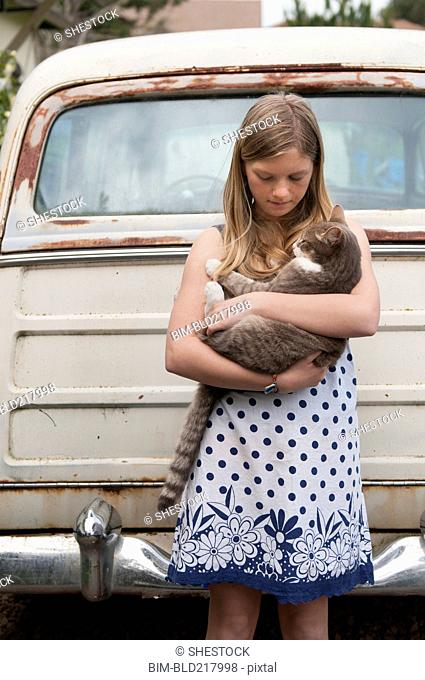 Girl holding cat near vintage car