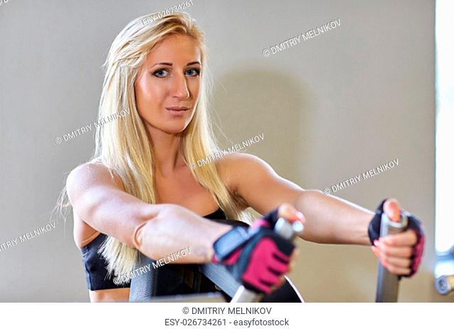 Sports woman doing exercises on power training apparatus in the gym
