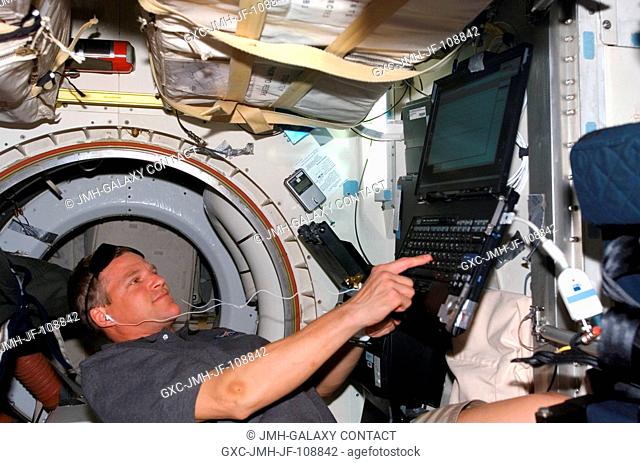 Astronaut Scott Parazynski, STS-120 mission specialist, uses a computer on the middeck of Space Shuttle Discovery while docked with the International Space...