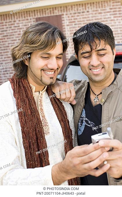 Close-up of a mid adult man with a young man looking at a mobile phone and smiling