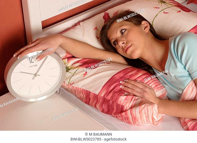 woman lying in bed watching clock, sleeplessness