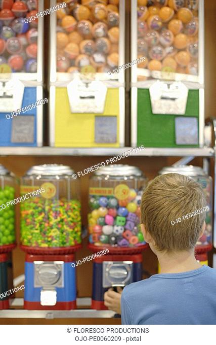 Young boy in store using gumball machine