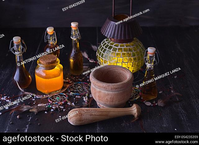 Magic luminous alchemy potions, old lantern on dark background over black wood with an Indian amulet