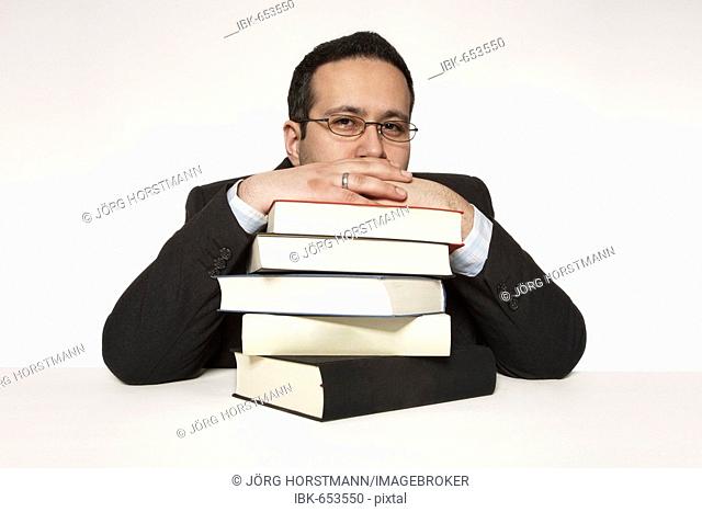 Man resting his chin on a stack of books
