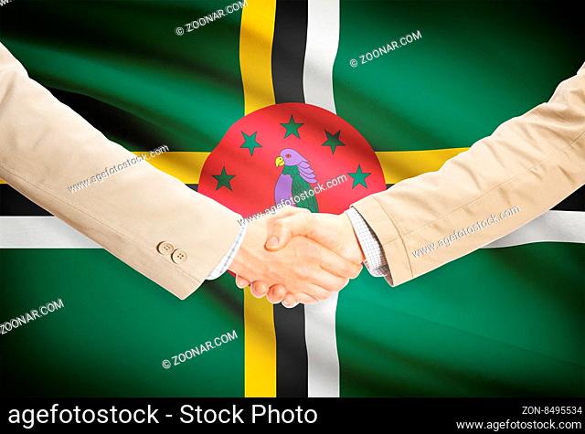 Businessmen shaking hands with flag on background - Dominica