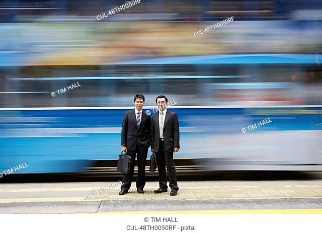 Businessmen standing by blurred bus